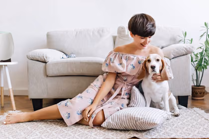 Oturma odasında, mutlu bir köpekle vakit geçiren kadın