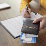 Pasaport ve başvuru formu ile visa (vize) başvurusunu hazırlayan kişi, belgeleri kontrol ederken bilgisayar başında çalışıyor.