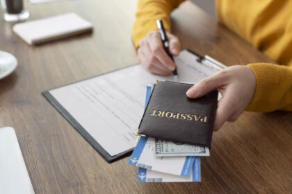 Pasaport ve başvuru formu ile visa (vize) başvurusunu hazırlayan kişi, belgeleri kontrol ederken bilgisayar başında çalışıyor.