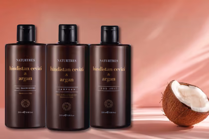 Hindistan cevizi ve argan yağı şişeleri ile doğal yağlar, taze hindistan cevizi ve argan meyvesi yanında.