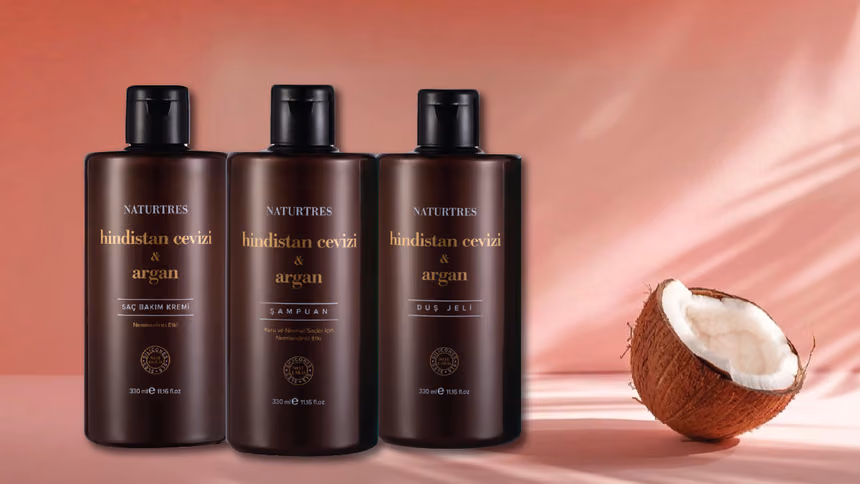 Hindistan cevizi ve argan yağı şişeleri ile doğal yağlar, taze hindistan cevizi ve argan meyvesi yanında.
